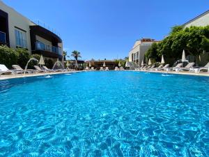 a large blue swimming pool with chairs and a building at Odyssey Residence Apartments in Fethiye