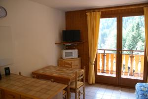 een kamer met een tafel, een magnetron en een balkon bij Ranfolly 10 in Morzine