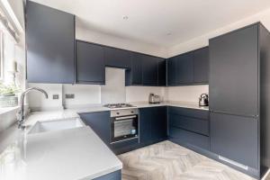 a kitchen with dark blue cabinets and a sink at Charming cottage in WINDSOR - WALK TO CASTLE &SHOPS! in Windsor