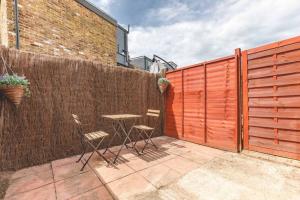 a patio with two chairs and a table in front of a fence at Charming cottage in WINDSOR - WALK TO CASTLE &SHOPS! in Windsor