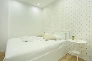 ein weißes Schlafzimmer mit einem weißen Bett und einem Tisch in der Unterkunft Rent a Room - 253, 2BDR Center of PARIS in Paris