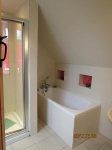 a white bathroom with a tub and a shower at The Thatched Cottage B&B in Claregalway