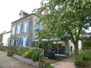 a brick house with blue windows and a tree at Chambre d'hotes de la Mousse in Saint Remy sur Orne