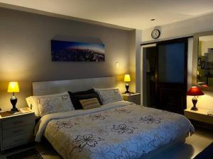 ein Schlafzimmer mit einem Bett, zwei Lampen und einer Uhr in der Unterkunft Apartaestudio El Lugar Ideal Cra. 62 #74-143. in Barranquilla