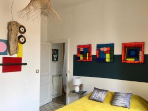 1 dormitorio con 1 cama y pinturas en la pared en La Casa Deva - Maison d Artistes, en Montredon