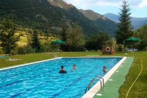 three people in a swimming pool with mountains in the background at Dúplex Àreu, Pallars in Areu