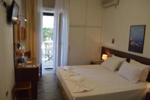 sypialnia z łóżkiem z białą pościelą i oknem w obiekcie Pergola w mieście Livadion