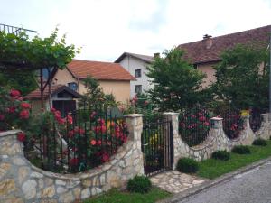 a stone fence with flowers in front of a house at Prenoćište " Ruža" in Višegrad