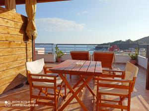 uma mesa de madeira e cadeiras numa varanda em Bourbos Summer Rooms em Himare