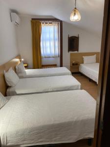 a hotel room with two beds and a window at Guesthouse Lusa Atenas in Coimbra