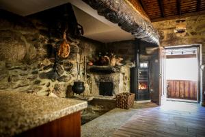 a kitchen with a stone wall with a fireplace at Casa das Afonsas in Barral