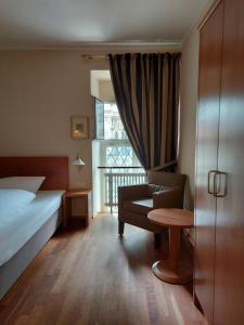 ein Schlafzimmer mit einem Bett, einem Stuhl und einem Fenster in der Unterkunft Hotel Kaiserhof am Dom in Regensburg