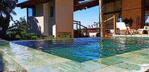 a swimming pool in front of a house at Haleiwa chalés e suítes - A Guest House do Prumirim in Ubatuba