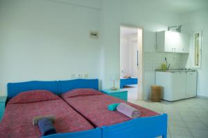 a bedroom with a blue bed and a kitchen at PortoAgali in Porto Koufo