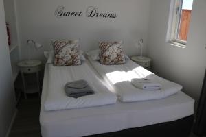 uma cama branca com toalhas e almofadas em Laxhús em Húsavík