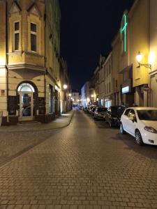 a city street at night with cars parked on the street at OficynaApartments in Gliwice