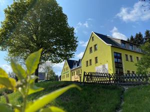 ein gelbes Haus mit einem Zaun davor in der Unterkunft Berghotel Talblick in Holzhau