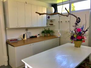 uma cozinha com armários brancos e uma mesa com flores em De Vlies em Venray