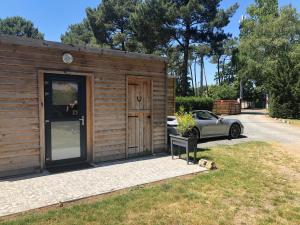 a small wooden building with a car parked next to it at Cabane du Circuit in Le Mans