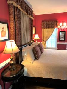 um quarto com uma cama com paredes vermelhas e uma janela em A Williamsburg White House Inn em Williamsburg