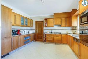a large kitchen with wooden cabinets and appliances at Villa Mikael - Free Wi-Fi - Aircon - Private Pool by bedzy in Albufeira