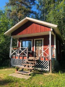 Cabaña pequeña con techo rojo y porche en Pihlajamäen Lomamökit en Vanhakylä