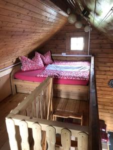Una cama en una cabaña de madera con sillas. en Ferienhaus Sterling en Luckau