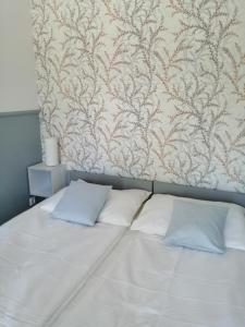 Una cama con sábanas blancas y almohadas en un dormitorio en Dom w Pobierowie, en Pobierowo