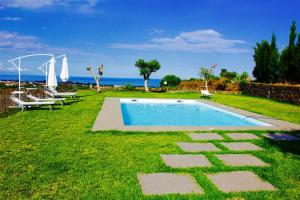 a swimming pool in a grassy yard with two chairs at B&B Il Vulcano in Aci Catena