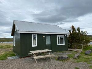 a green shed with a picnic table in front of it at Ábót - Riverside Cottage in Egilsstadir