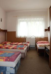 a group of three beds in a room with a window at Penzion Bezděkov in Rakovník