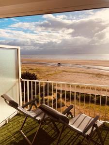a rocking chair on a balcony with a view of the beach at Appartement "Envies D'ailleurs" Vue Mer in Saint-Brevin-les-Pins