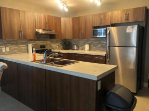 a kitchen with a stainless steel refrigerator and wooden cabinets at Signature Suites By Oasis Corporate Rentals in Grande Prairie
