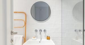bagno bianco con lavandino e specchio di Cozy Lisbon Alfama a Lisbona