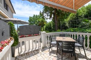 eine Terrasse mit einem Tisch und Stühlen auf einem weißen Zaun in der Unterkunft Apartments Villa Salona in Opatija
