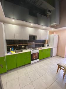 a kitchen with green cabinets and a white refrigerator at Апартаменты новострой улица Замостянская 34 А in Vinnytsya