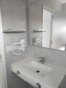 uma casa de banho com um lavatório branco e um espelho. em A Postiña em Areas