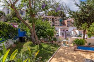 a garden with a tree and a swimming pool at Blue Castle GuestHouse in Málaga
