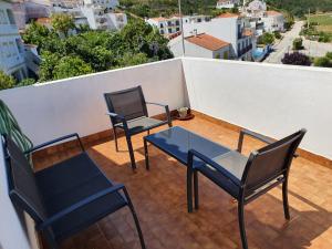 two chairs and a glass table on a balcony at Hospedaria Firmino Bernardino in Odeceixe +80 photos