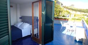 a bedroom with a bed and a table on a balcony at Hotel Baia Di Puolo in Massa Lubrense