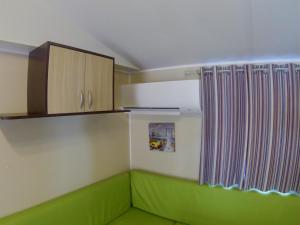 a room with a green couch and wooden cabinets at L europe in Vic-la-Gardiole