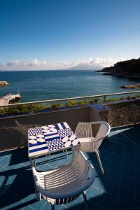 a table and chairs on a balcony overlooking the ocean at Hotel Baia Di Puolo in Massa Lubrense