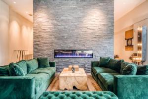 a living room with green couches and a fireplace at Lodgeur at Mid Main Lofts in Houston
