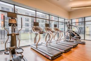 una fila de máquinas de cardio en un gimnasio con ventanas en Lodgeur at Mid Main Lofts, en Houston