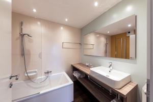 een badkamer met een wastafel, een bad en een spiegel bij Hotel Berghang in Collepietra