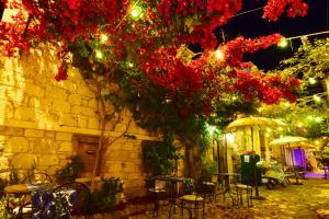 a group of tables and chairs under a tree with red flowers at Rue d'Azur Alaçatı in Alaçatı