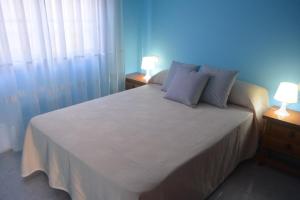 a bedroom with a white bed with two lamps at Apartamentos baltar sanxenxo 1 in Sanxenxo