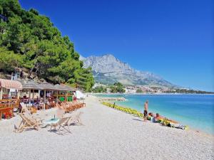 a beach with a group of people sitting on the beach at Villa Rosso in Baška Voda