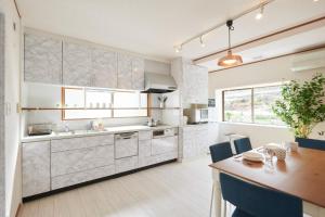 a kitchen with white cabinets and a wooden table at Ryoshi Minpaku CHOUTA - Vacation STAY 7955 in Awaji