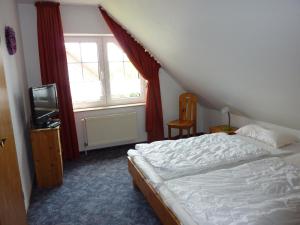 a bedroom with a bed and a tv and a window at Ferienhaus Marion in Neßmersiel